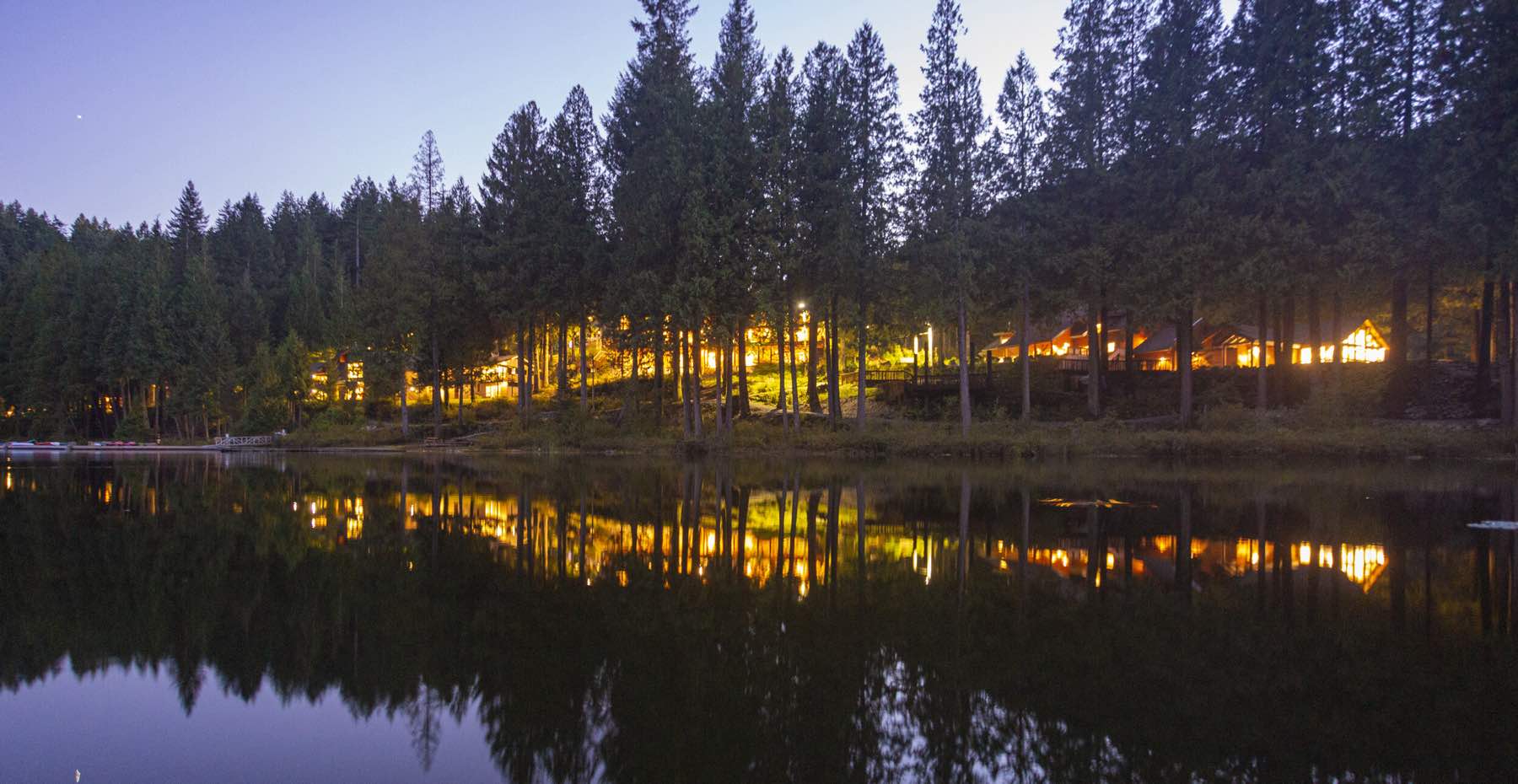 Lodge and Retreat Centre illuminated at dusk, reflecting in the lake
