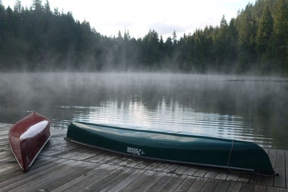 two canoes on a lakeside dock in the morning mist